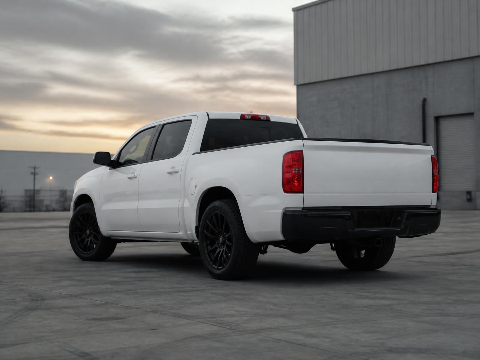 White crew cab pickup truck in a concrete lot at dawn